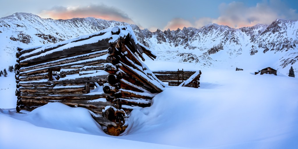 This Rugged Mountainscape taken near Mayflower Gulch, Colorado was taken at sunrise and features some mining ruins, covered in fresh, drifted snow, with an amphitheater of craggy Rocky Mountain peaks behind it.