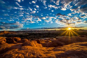 Exploring various locations within Canyonlands National Park, Utah, Clark Schiring captured this scene just as the sun set behind the Needles District. With flowing red rocks typical of Moab-area landscapes, this fine art photography image creates a dramatic, yet calming feeling for the viewer. It was shot low to the ground using a wide-angle lens to showcase the dramatic sky, as well as the rocks below.